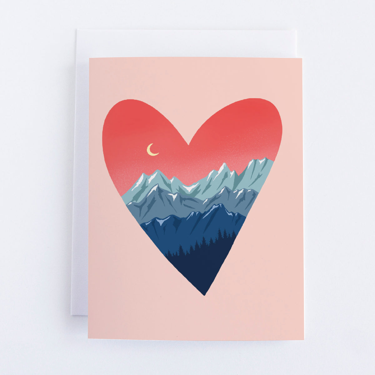 A light pink card with a dark pink hear that has three rows of blue mountains at the bottom of the heart and a row of trees. In the top left of the heart is a crescent moon.