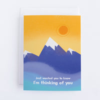 An orange card with blue snow capped mountains and the text in front of the mountains says Just Wanted You To Know Im Thinking of You.
