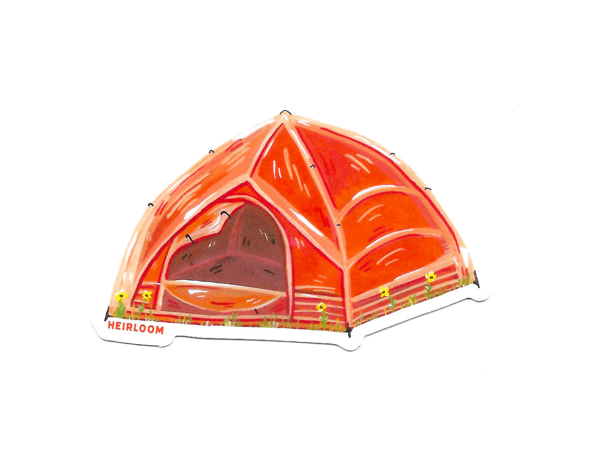 A hand painted orange tent that is staked in the ground and the door to the tent is rolled open so you can just see the back corner of the tent. It is sitting in grass with little yellow flowers.